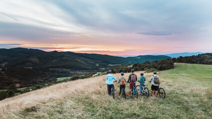 Multigenerational biking trip in nature. Family looking at sunset.