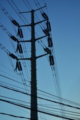 close-up of a high voltage electricity pole with multiple power lines and insulators, silhouetted...