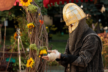 knight helmet and gothic urban cloak on wounded unrecognizable male person in natural decoration...