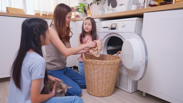 Asian beautiful mother teaching young daughters doing laundry at home.