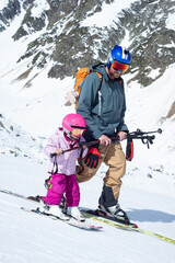 A father and his 3-year-old daughter enjoying a ski day.