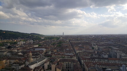 A panoramic view of the Torino skyline, with rays of sunlight breaking through the clouds and the majestic Alps visible in the background.