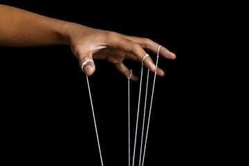 male puppeteer hand with strings isolated on black background. manipulation or controlling concept