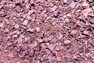Textured purple gravel covering the ground in a natural landscape during bright daylight