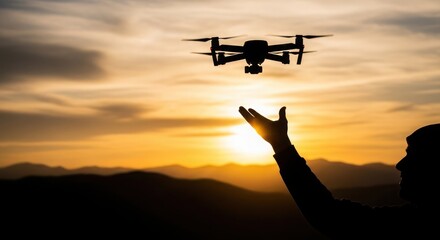A person reaches towards a drone silhouetted against a vibrant sunset sky.