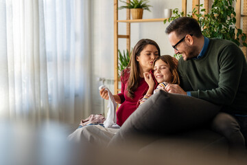 Happy parents, teen daughter having pleasant conversation, laughing chatting at home. Family weekend