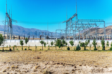 An electric substation located in a valley among high mountains, in summer against a blue sky...