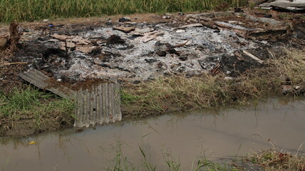 buildings that were burned and reduced to ashes beside the river near the rice fields