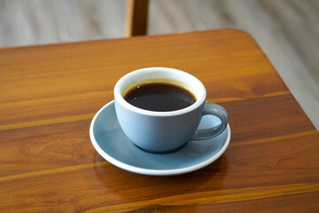 Obraz premium Hot Americano Coffee, captured on September 1, 2025. Steaming black coffee served in white ceramic cup on wooden table, cozy minimalist style, perfect for café, breakfast, and lifestyle themes