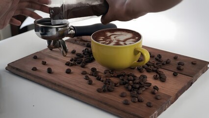 Barista preparing latte art in a yellow mug with coffee beans