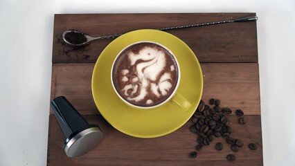 Latte Art Seahorse on a Yellow Cup with Coffee Beans and Tools