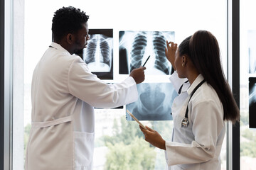 Doctors collaborating near window with X-rays, highlighting medical expertise in diagnostic...