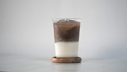 A simple and refreshing iced latte coffee in a clear glass on a white background