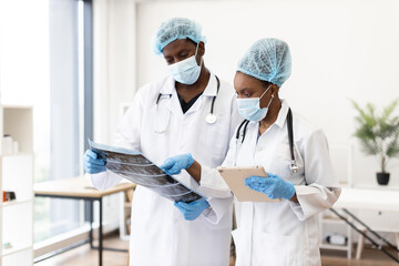 Two adult healthcare professionals, male and female, wearing masks, discussing radiographic tests...