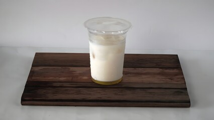 A cold milk drink in a plastic takeaway cup on a dark wooden board