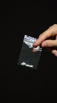 Drug trafficking and drug business,
Drug dealer passes on an order to a client.
Consumption of narcotic psychotropic substances by a drug addict.
A faceless man holds a ziplock bag with LSD pills
