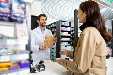 Obraz premium Young dark-haired caucasian woman buying medicines in the pharmacy