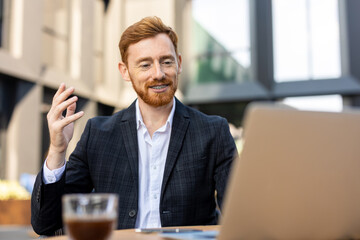 Red-haired man smiling while having video conference