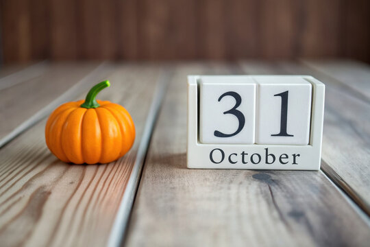 Autumnal Charm A Wooden Tabletop Displaying a Calendar Block Set to October 31st with a Miniature Pumpkin Decoration