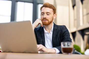 Confident focused man entrepreneur in suit working outdoors on computer