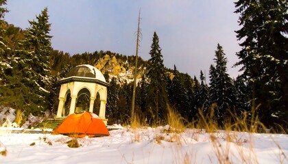 Orange tent in snowy landscape with gazebo