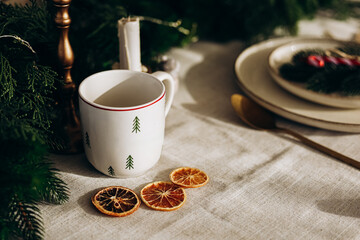 Warm cup of tea with dried orange slices on a festive table setting