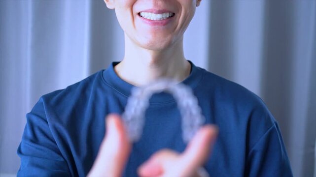 Clear Dental Aligners or braces. Orthodontic Mouthpiece  that a smiling person held in hand. Slow motion video.