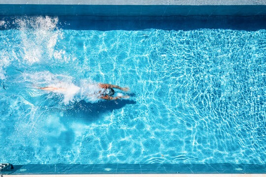Aerial overhead view of a man jumping and diving into a swimming pool with copy space