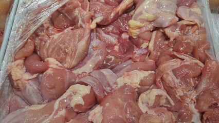 Close-up of fresh raw chicken fillet pieces displayed at a market or store, showcasing uncooked poultry meat with natural texture, color, and detail for food industry use