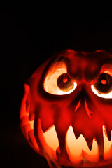 Fototapeta premium Creepy carved pumpkin glowing inside with fog flowing out, creating a spooky Halloween mood on a black background.