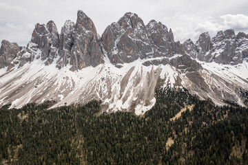 Sharp peaks of the Dolomites mountains rising above forest in Italy. Aerial view