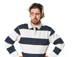 Young Caucasian man in studio setting confused, feels doubtful and unsure.