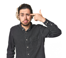 Young Caucasian man in studio setting showing a disappointment gesture with forefinger.