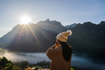 Young woman traveler taking a beautiful landscape at sunrise over the mountains, Travel lifestyle concept