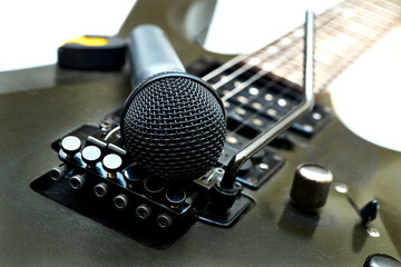 A vocal microphone rests on the body of an electric guitar