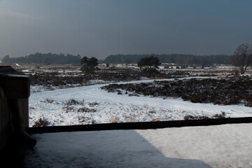 Snowy heathland landscape viewed through window frame, winter morning scene with overcast sky