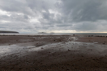 Expansive Welsh beach at low tide with distant headlands under overcast sky