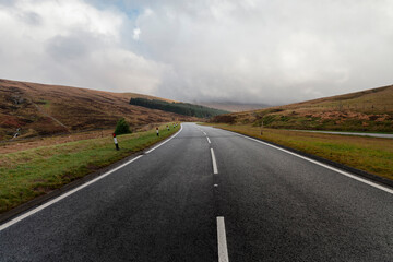 Empty Welsh road stretching through moorland toward forested hills