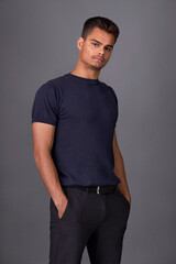 Attractive young brunette with short haircut in black trousers and grey T-shirt posing in studio on...