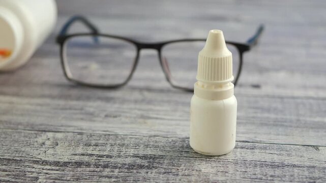 Eye drop bottle placed near reading glasses on table