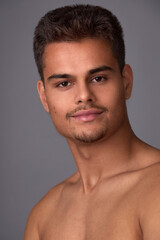 Obraz premium Portrait of an attractive young brunette with a short haircut and light stubble on a gray background