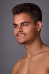 Naklejka premium Portrait of an attractive young brunette with a short haircut and light stubble on a gray background