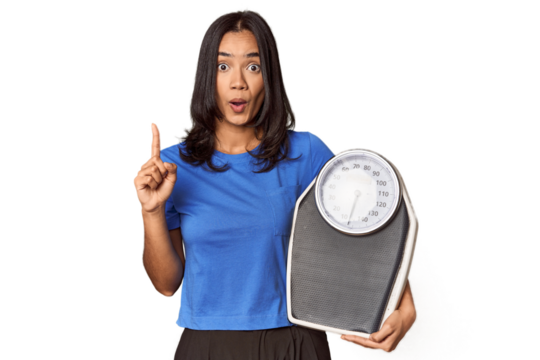 Filipino woman with scale in studio having some great idea, concept of creativity.