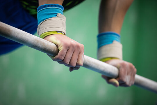 Close up of a gymnastics athlete gripping a sports bar with white chalk on their hands - Powered by Adobe