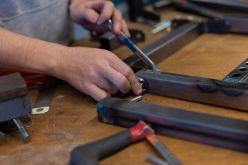 Hands using screwdriver to assemble metal components in workshop environment