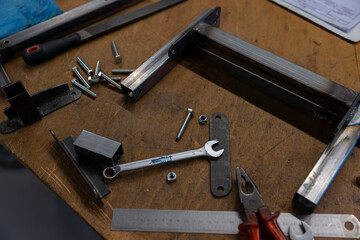 Various metal tools screws nuts and clamps organized on wooden workbench