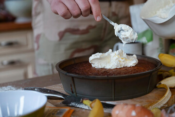 Hand spooning whipped cream onto chocolate dessert in cast iron cooking pan