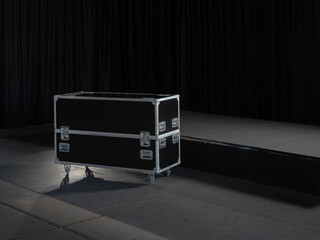 Black professional flight case with wheels positioned on dark stage for equipment transport
