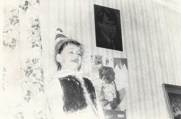 Boy in Pinocchio costume celebrates joyfully at Christmas carnival, captured in black-and-white film photography from early 1990s in Ukraine