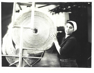 Black and white analog photo of a young woman working near a jute loom at the Odessa Jute Factory, early 1980s Ukrainian SSR, industrial atmosphere